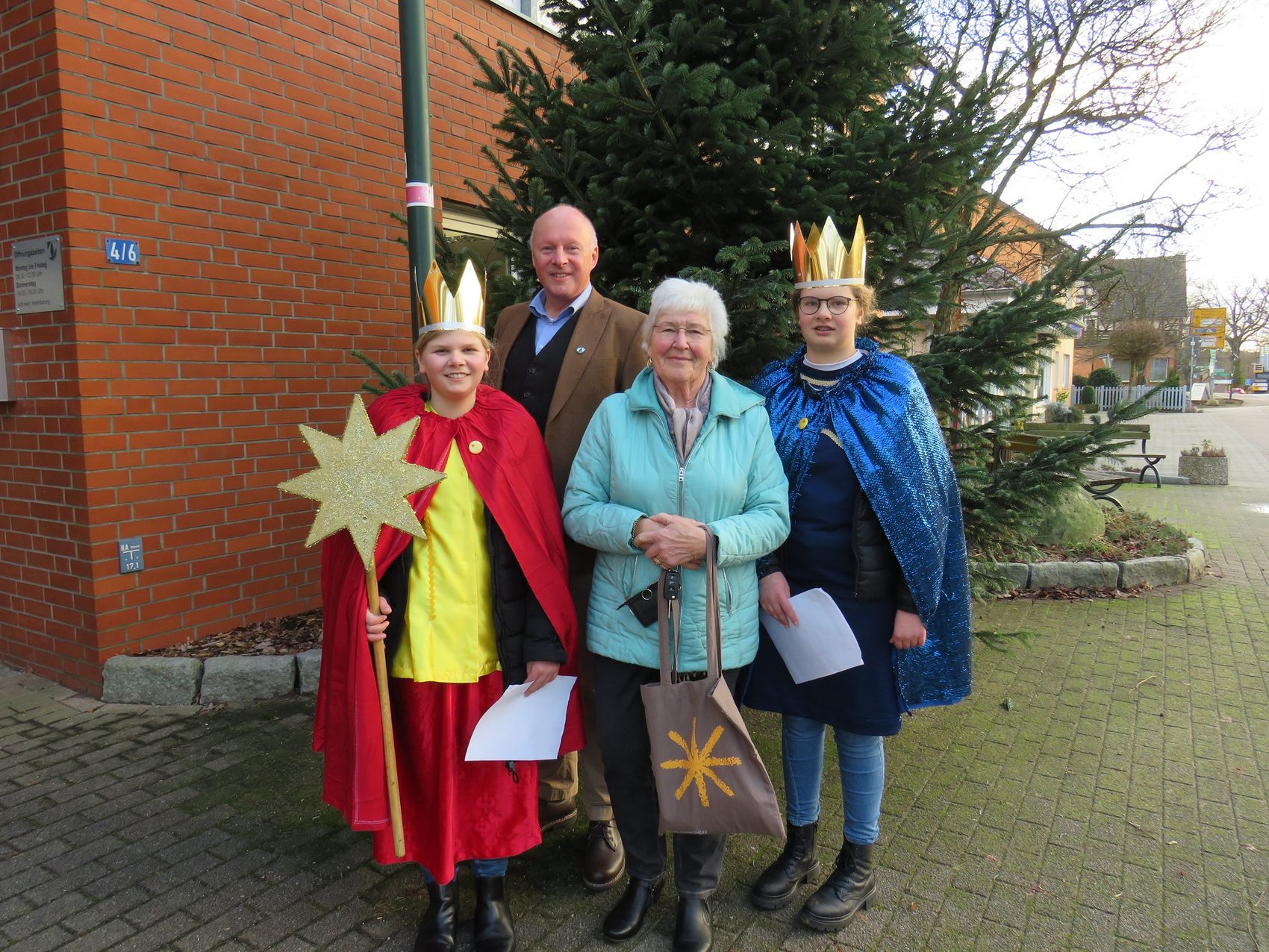 Das Foto zeigt Bürgermeister Dr. Jens Bülthuis, zwei Sternsingerinnen und deren Begleitung Ilka Siemsglüß vor dem Bispinger Rathaus.