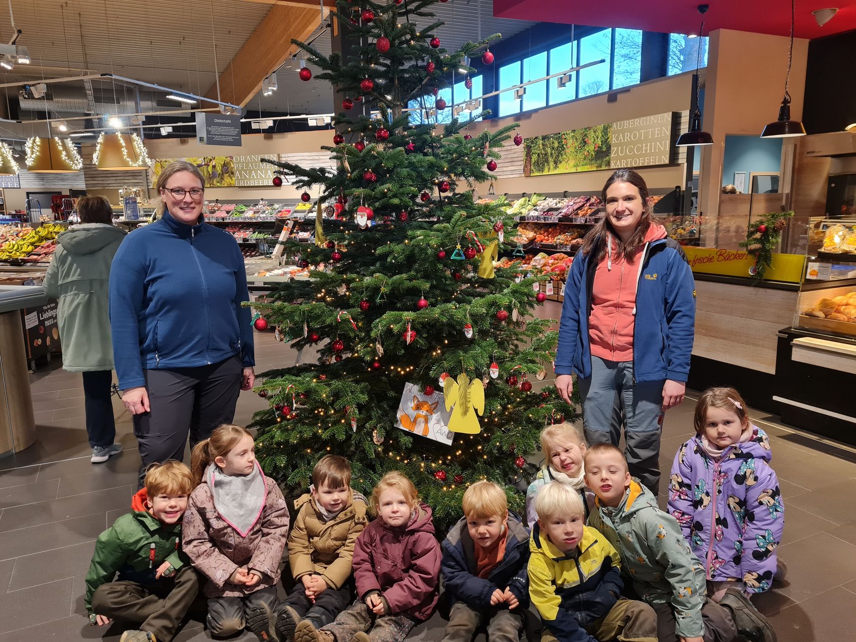 Das Bild zeigt die Gruppe des AWO-Waldkindergartens vor dem geschmückten Weihnachtsbaum.