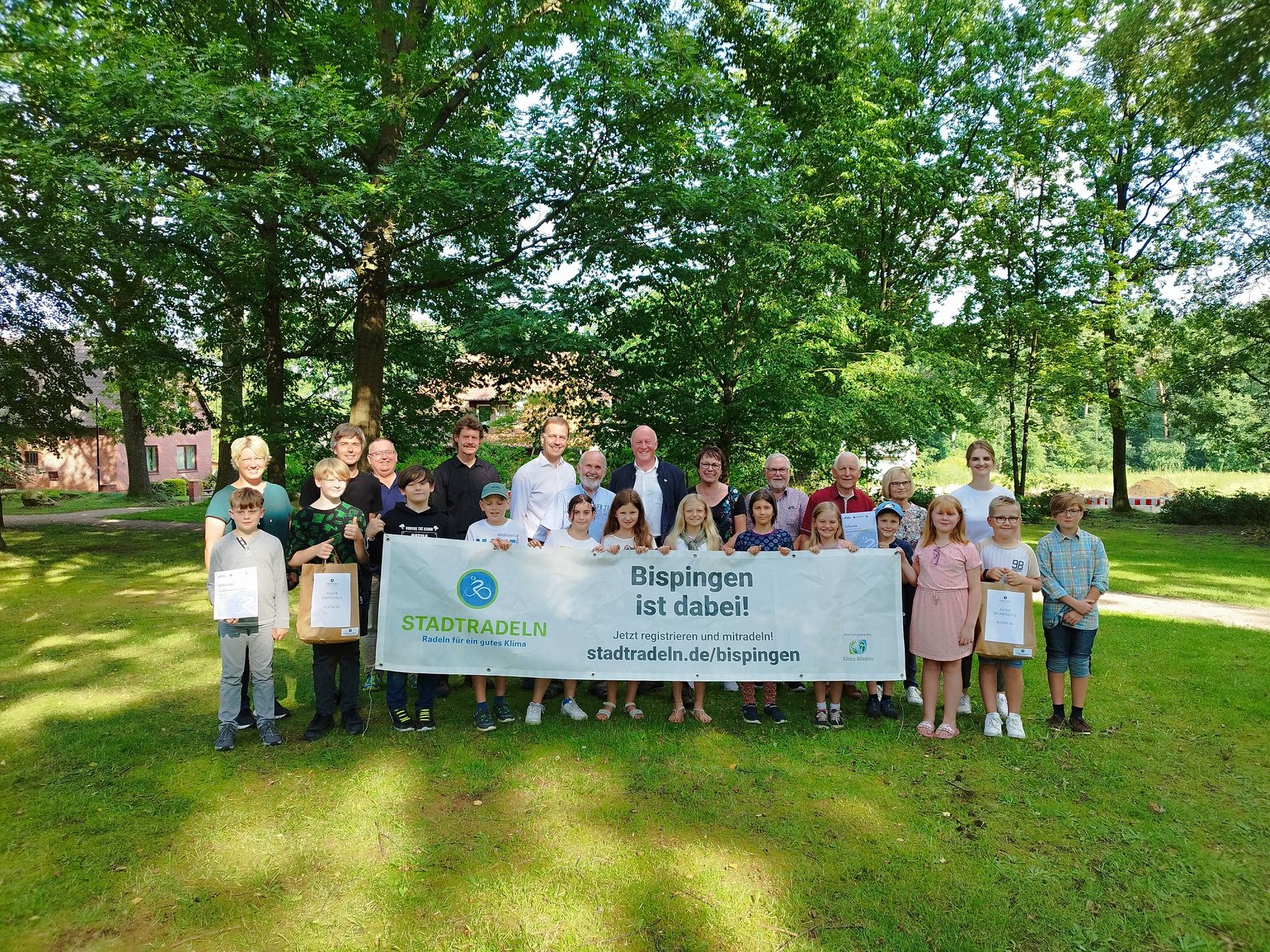 Bürgermeister Dr. Jens Bülthuis würdigt die Gewinnerteams des Stadtradelns in Bispingen Das Bild zeigt die Gruppe der Geehrten, die den Banner