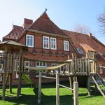Backsteingebäude der Kita Behringen mit Spielplatz und Klettergerüst im Vordergrund