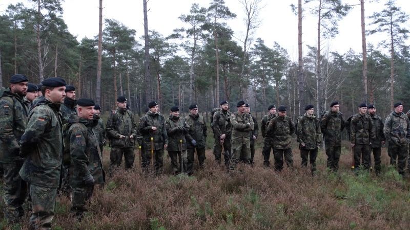 Soldaten der Patenkompanie stehen im Wald und führen eine Entkusselungsaktion durch.