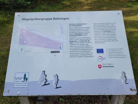 Informationstafel zur Hügelgräbergruppe Behringen mit Lageplan, Text zur Geschichte der Gräber und Logos von Naturschutzverein und Niedersachsen