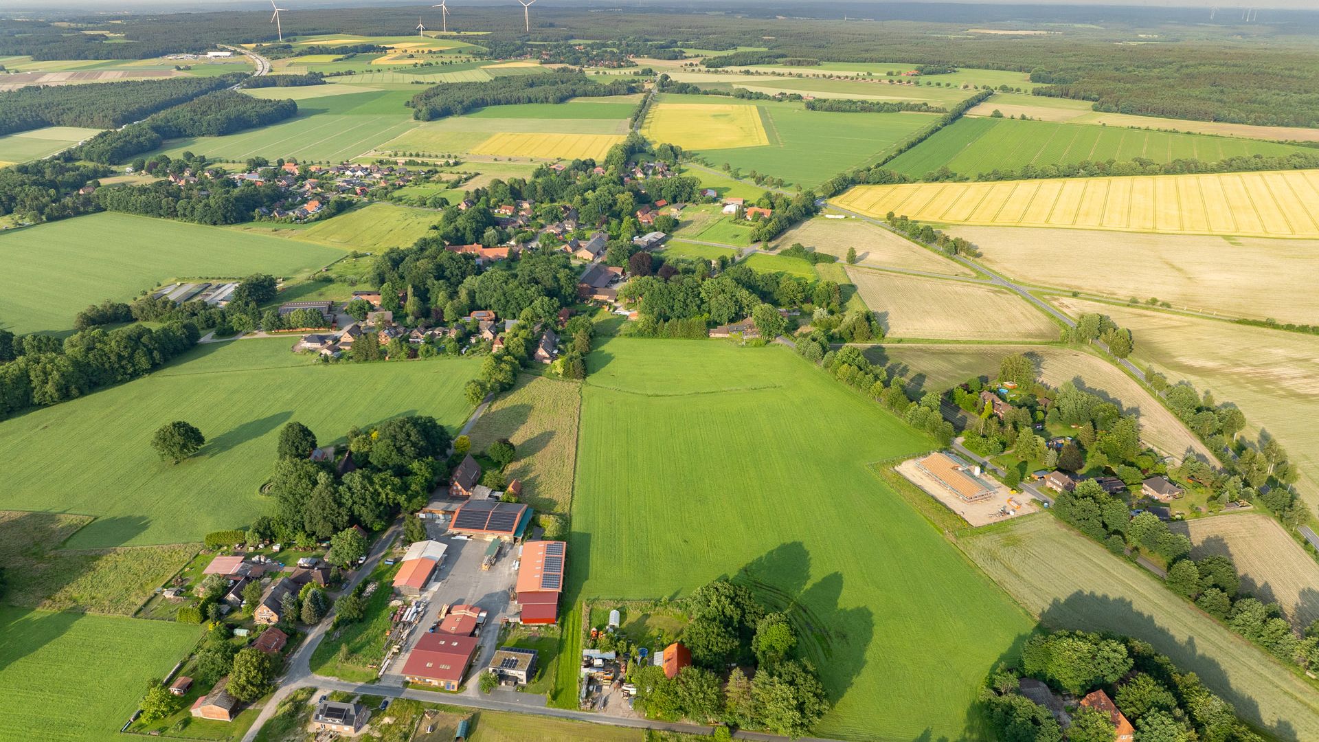 Luftbildaufnahme von Hoerpel 2024, zeigt eine weitläufige Landschaft mit Feldern, Wäldern und einem kleinen Ort im Vordergrund.