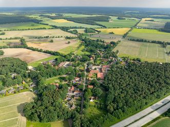 Luftaufnahme von Volkwardingen 2024, zeigt eine ländliche Umgebung mit Feldern, Wäldern und einem kleinen Dorf im Vordergrund.