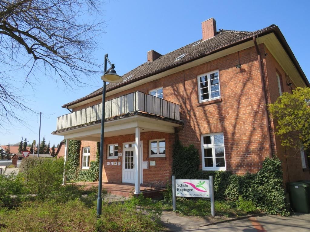 Außenansicht des Backsteingebäudes der GOBS Bispingen mit Eingangsbereich, Balkon und Schild 'Schule Bispingen'