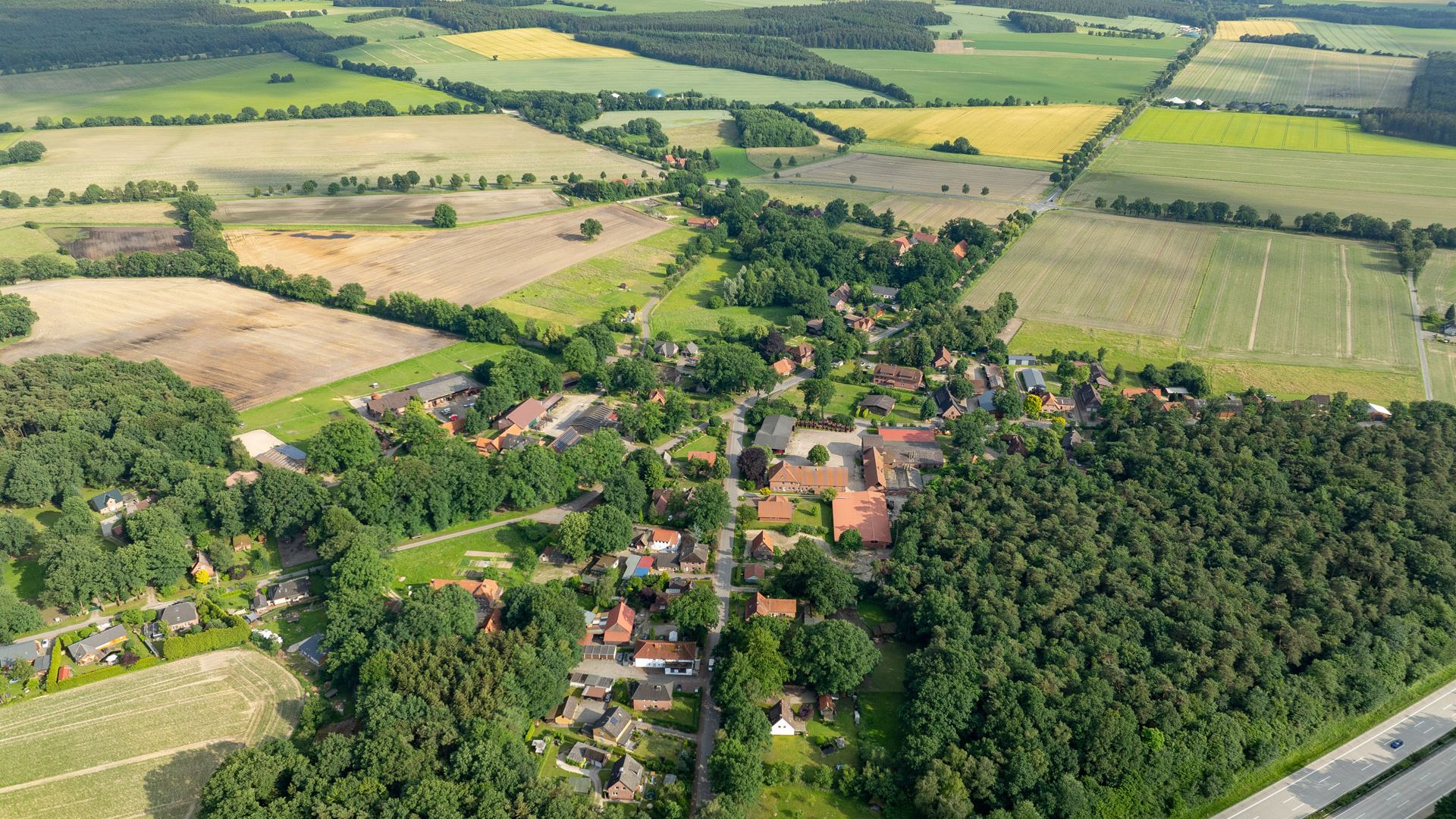 Luftaufnahme von Volkwardingen 2024, zeigt eine ländliche Umgebung mit Feldern, Wäldern und einem kleinen Dorf im Vordergrund.