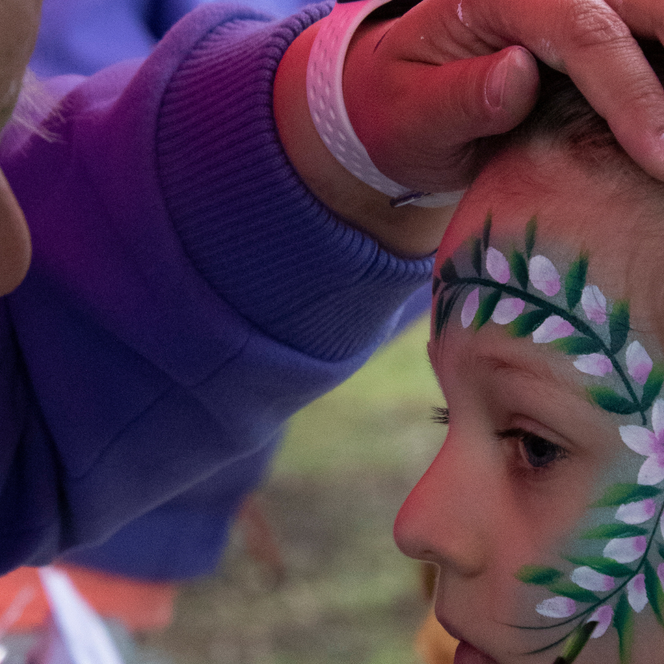 Hand mit Armband berührt den Kopf einer Person mit Ohrring und Haarspange und schminkt diese.