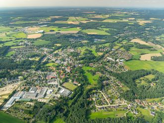 Luftbildaufnahme von Bispingen 2024, zeigt eine weitläufige Landschaft mit Wohngebieten, Feldern und Wäldern.