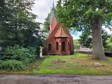 Kirche Hörpel, eine kleine Backsteinkirche mit spitzem Turm, umgeben von Bäumen und Grünflächen
