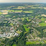 Luftbildaufnahme von Bispingen 2024, zeigt eine weitläufige Landschaft mit Wohngebieten, Feldern und Wäldern.