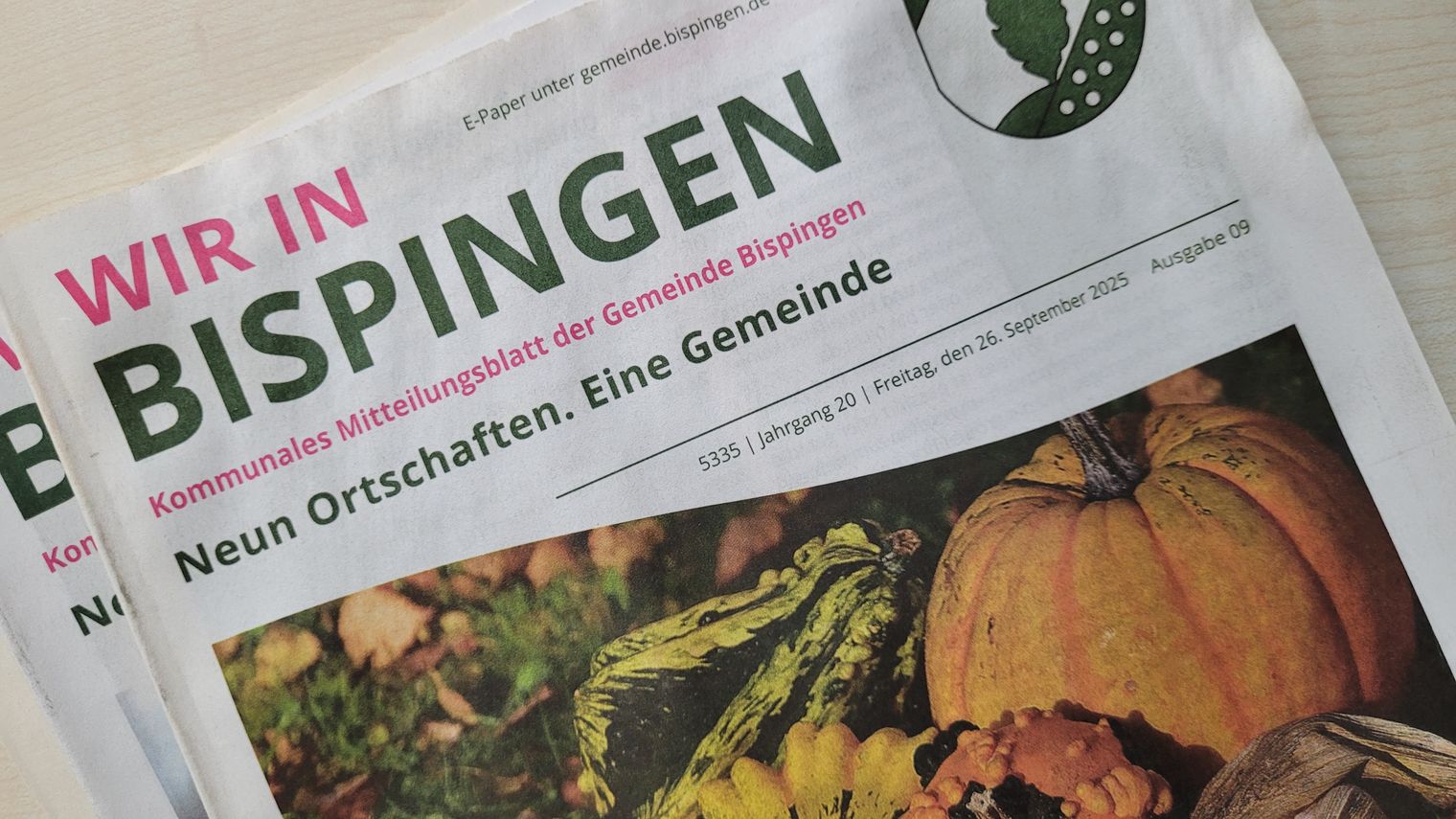 Zeitung mit der Überschrift 'WIR IN BISPINGEN' und dem Untertitel 'Kommunales Mitteilungsblatt der Gemeinde Bispingen'. Daneben Kürbis und Zierkürbisse auf Holzuntergrund.