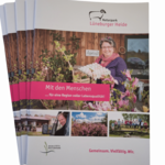 Informationsbroschüre des Naturparks Lüneburger Heide mit einer Frau, die Eier hält, und drei kleinen Fotos darunter mit Landschaft und Menschen.