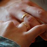 Zwei Hände mit goldenen Eheringen, die sich berühren