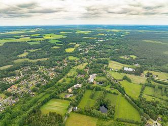 Luftbildaufnahme einer ländlichen Landschaft mit Feldern, Wäldern und verstreuten Wohngebieten. Sicht auf Huetzel 2024.