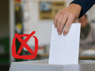 Hand legt weißen Wahlzettel in Wahlurne mit rotem Kreuzsymbol im Vordergrund