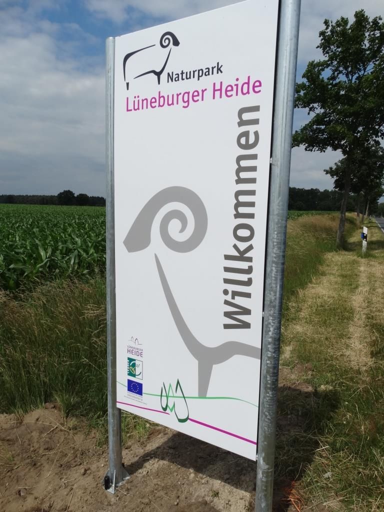 Willkommensschild des Naturparks Lüneburger Heide mit stilisierter Schafsgestalt und Schriftzug 'Willkommen'